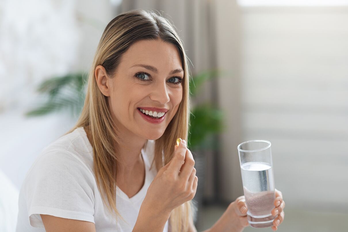 Frau mit Kapsel und Glas Wasser